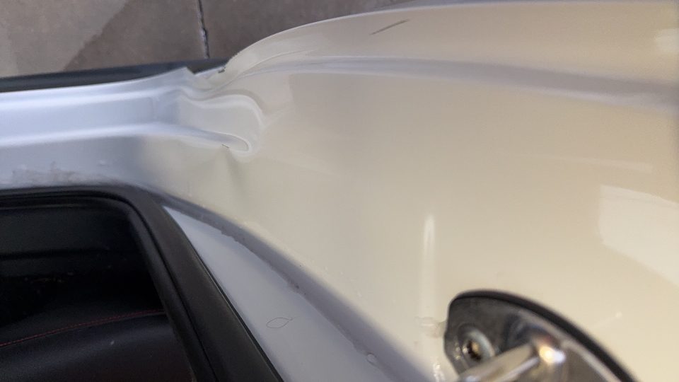 Volkswagen GLI en processus de peinture en cabine après réparation des dommages de carrosserie.