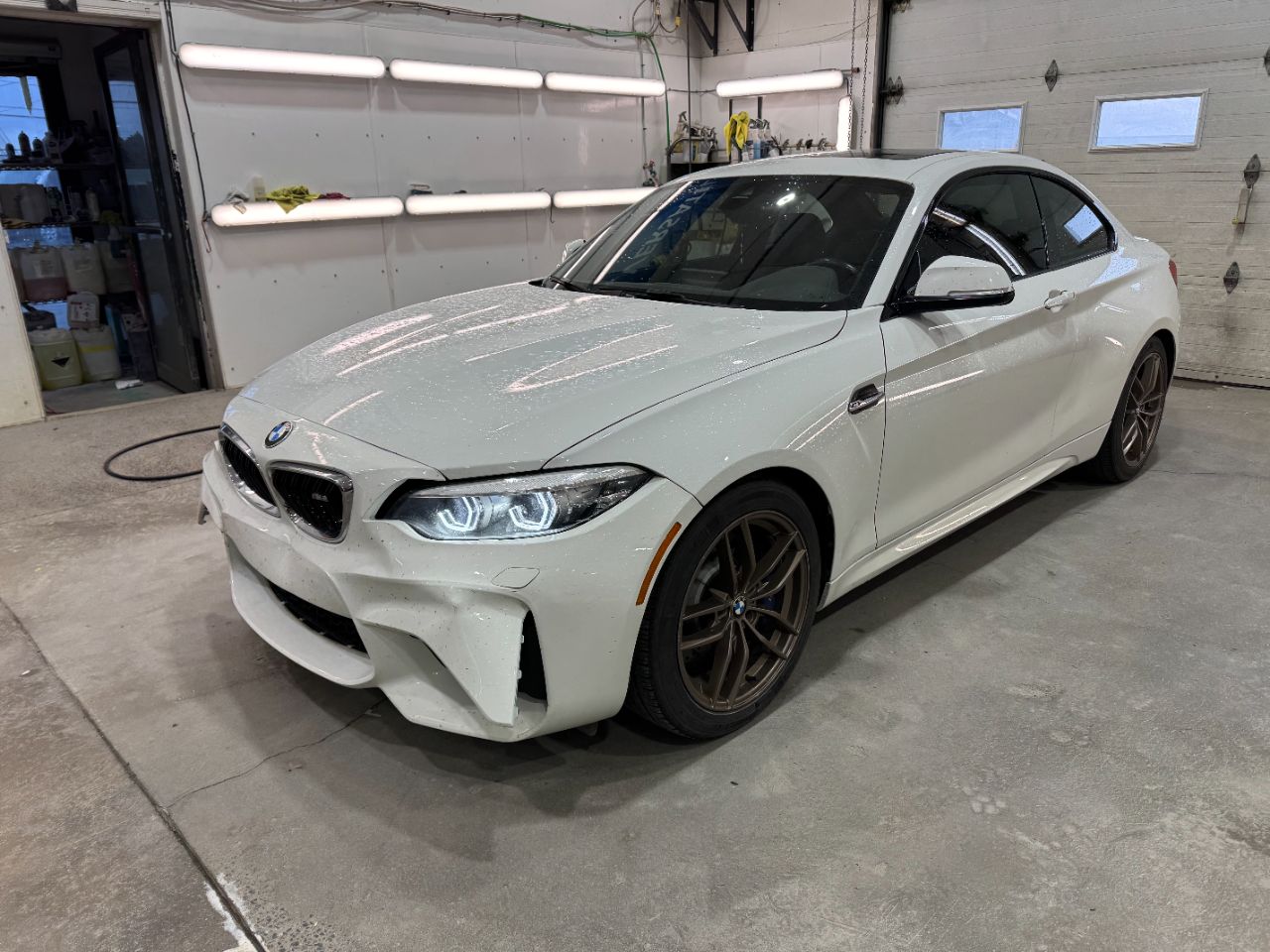 BMW M2 blanche vue avant gauche, dans l’atelier avant réparation